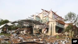 People speak on their phones in front of a house damaged by an explosion at a firework warehouse in Narathiwat province southern Thailand July 29, 2023. At least nine people were killed in the blast.