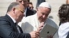 FILE - Pope Francis looks at an iPad at the end of his weekly general audience, in St. Peter's Square at the Vatican, June 7, 2017. (L'Osservatore Romano/Pool Photo via AP)