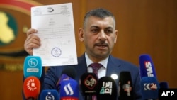 FILE - Haider Hanoun, the head of Iraq's Commission for Integrity, the government's anti-corruption agency, displays a document during a press conference in Baghdad, June 22, 2023, concerning cases uncovered by the commission.