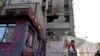 A resident walks past a partially destroyed residential building in Kyiv after a Russian drone strike, May 28, 2023. 