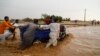People push a vehicle through muddy flood water along a street, following torrential rain in Saqqai near Omdurman, Sudan, Aug. 5, 2023. 