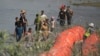 FILE - Migrants trying to enter the US from Mexico approach the site where workers are assembling large buoys to be used as a border barrier along the banks of the Rio Grande in Eagle Pass, Texas, July 11, 2023. 