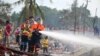 A fireman sprays water after an explosion occurred at a fireworks warehouse in Narathiwat province southern Thailand, July 29, 2023. At least nine people were killed, officials said.