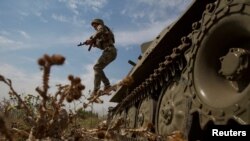 Війна триває майже півроку. Український військовослужбовець вистрибує з військової машини біля лінії фронту в Миколаївській області, Україна, 10 серпня 2022 року.