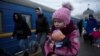 FILE - A girl holds a doll as civilians fleeing Russia's invasion of Ukraine board a train, in Odessa, Ukraine, March 8, 2022.