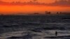 FILE - A man wades into the ocean at sunset on June 22, 2021, in Newport Beach, Calif. The National Oceanic and Atmospheric Administration said June 3, 2022, that the amount of carbon dioxide in the atmosphere in May averaged 421 parts per million, more t