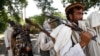 FILE - In this Sunday, July 31, 2011 file photo, Taliban fighters hold their heavy and light weapons before surrendering them to Afghan authorities in Jalalabad, east of Kabul, Afghanistan. 