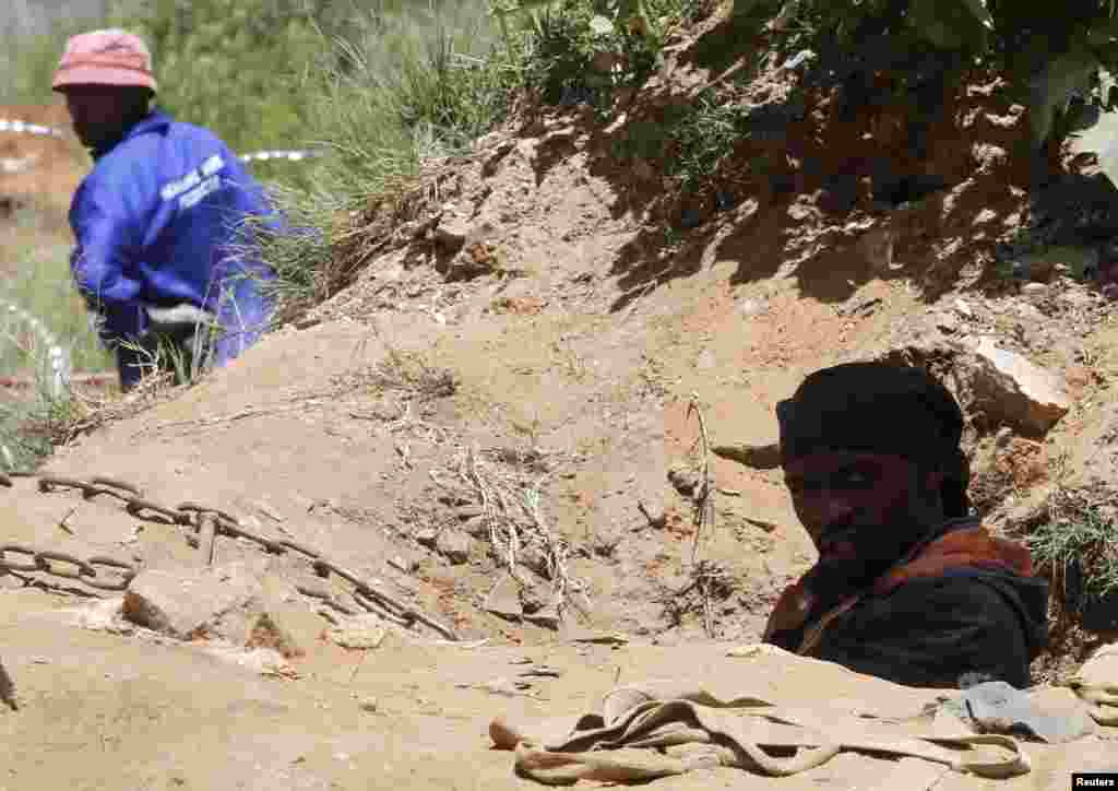 A suspected illegal miner climbs out of a ventilation shaft used to access an abandoned gold shaft in Benoni, east of Johannesburg, South Africa, Feb. 17, 2014. 