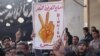 Anti-Syrian regime protester holds up Arabic placard reading: "the victory fingers over the [presidential] palace," during a demonstration, at Binnish village, in Idlib province, Syria.