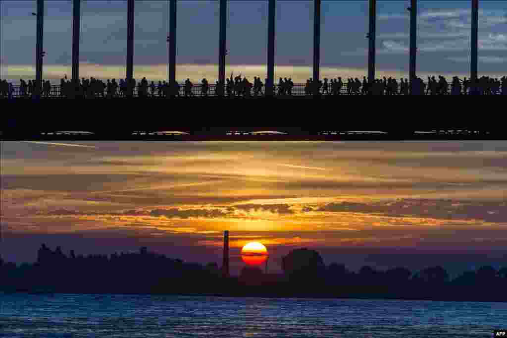 Walkers cross the Waalbrug River during sunrise on the first day of the 98th annual four-day walking event &quot;The Vierdaagse&quot; in Nijmegen, The Netherlands.