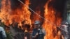 An Afghan policeman stands guard as smoke and flames rise from the site of a huge blast struck near the entrance of Kabul's international airport, in Kabul on August 10, 2015. 