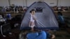 Syrian girl, Raghad Hussein, 3, who fled her home with her family due to fighting between the Syrian army and the rebels, stands by her family's makeshift tent, near Azaz, Syria, Aug. 26, 2012.