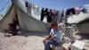 A Syrian refugee boy sits outside his family's tent at a temporary camp in the Lebanese town of Marj near the border with Syria, May 20, 2013. 