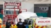 Police officers are on the scene after a truck, in rear, was found to contain a 39 dead bodies, later found to be Chinese nationals, in Thurrock, England, Oct. 23, 2019. 