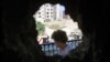 A woman is seen from a hole in her home's wall, caused by clashes between Sunni Muslims and Alawites in Tripoli, northern Lebanon, August 27, 2012. 