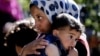 A Syrian refugee carries her sister in a refugees camp near the Lebanonese village of Ketermaya in March.