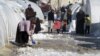 A Syrian refugee uses a toy shovel to remove snow from outside her tent at Bab al-Salam refugee camp in Syria, near the Turkish border, January 10, 2013. 