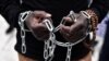 FILE - An African migrant with his hands chained takes part in a march toward the offices of the European Union during a demonstration on Dec. 2, 2017, in central Athens, protesting against the slavery of migrants in Libya.