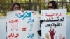 Women hold banners during a demonstration for women's rights in Tripoli. The poster on the left reads, "Quota: Since two women equal one man (in Sharia law), there should be two women for every man in parliament. Then the formula will be perfect." Feb. 7, 2013.