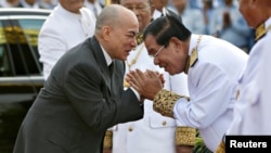 FILE - Cambodia's King Norodom Sihamoni is greeted by prime minister Hun Sen during the celebration marking the 64th anniversary of the country's independence from France, in Phnom Penh, Cambodia, Nov. 9, 2017.