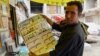 An Afghan store clerk shows a calendar with pictures of Afghan leaders including Mullah Mohammad Omar, bottom row, second left, in Kandahar, south of Kabul, Afghanistan, July 30, 2015. 