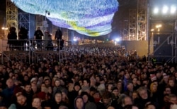 Visitors stay underneath the skynet artwork "Visions In Motion" in front of the Brandenburg Gate as they attend stage presentations to celebrate the 30th anniversary of the fall of the Berlin Wall in Berlin, Germany, Nov. 9, 2019.