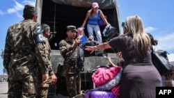FILE - Venezuelans get off a Brazilian army truck after being given a ride by Brazilian soldiers while crossing the Brazilian-Venezuelan border, into Pacaraima, Roraima state, Brazil, Feb. 27, 2019.