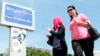 Women walk past a poster of the play ?Made in Tunisia, 100 percent halal? by Tunisian actor, playwright Lotfi Abdeli. The play was boycotted previously by hundreds of Salafi Muslims who believed the show was offensive to Islam, (File Photo).