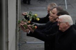 Presidents Frank-Walter Steinmeier of Germany, Janos Ader of Hungary, Andrzej Duda of Poland, Zuzana Caputova of Slovakia and Milos Zeman of the Czech Republic, from right, put flowers in a crack inside the Berlin Wall, Nov. 9, 2019.
