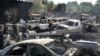 Sejumlah orang mencari barang-barang yang masih bisa diselamatkan dari mobil-mobil yang hangus dibakar massa saat kekerasan oleh geng-geng bersenjata di Port-au-Prince, Haiti, 25 Maret 2024. (Foto: Odelyn Joseph/AP Photo)