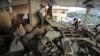 A Palestinian woman, left, cries inside her damaged house, which police said was targeted in an Israeli airstrike in Gaza City, July 17, 2014. 