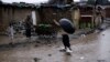 Pakistani man crossing flooded path during heavy rain fall in slum on outskirts of Islamabad, Pakistan (2013 photo)