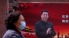  2020年3月12日，新冠病毒爆发期间，一名戴口罩的妇女从上海街头的一副中国国家主席习近平的宣传图像前走过。
