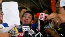 Maria Ressa, left, the award-winning head of a Philippine online news site Rappler that has aggressively covered President Rodrigo Duterte's policies, shows her release order after posting bail, Feb. 14, 2019 in Manila, Philippines. 