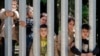 FILE - Members of a group of some 30 migrants seeking asylum are seen in Bialowieza, Poland, on Sunday, 28 May 2023 across a wall that Poland has built on its border with Belarus to stop massive migrant pressure.
