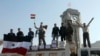 Soldiers loyal to the regime and civilians holding the Syrian national flag stand near boxes containing aid from the Syrian army in Qusair, June 5, 2013. 
